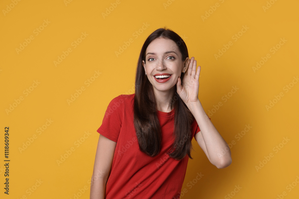 Woman showing hand to ear gesture on orange background Woman showing hand to ear gesture on orange background