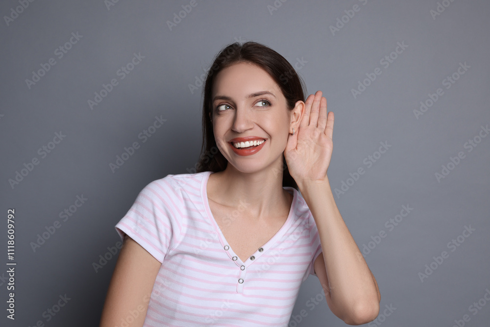 Woman showing hand to ear gesture on grey background Woman showing hand to ear gesture on grey background