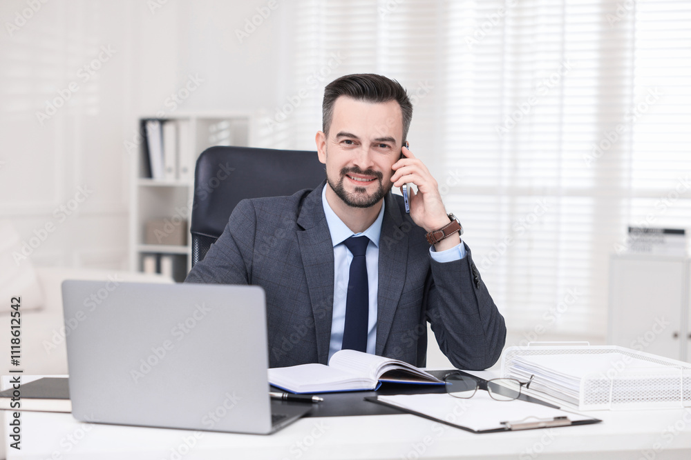Happy banker talking on smartphone at table in office Happy banker talking on smartphone at table in office