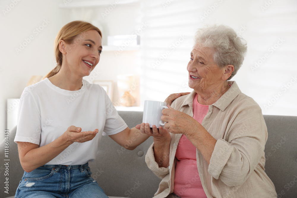 Caregiver supporting senior woman on sofa at home Caregiver supporting senior woman on sofa at home