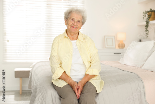 Beautiful senior woman sitting on bed at home