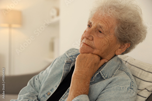 Loneliness concept. Sad senior woman sitting on sofa at home