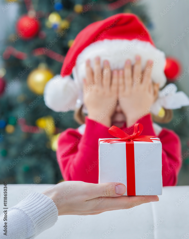 Portrait of little cute girl in Santa Claus costume with Christmas present