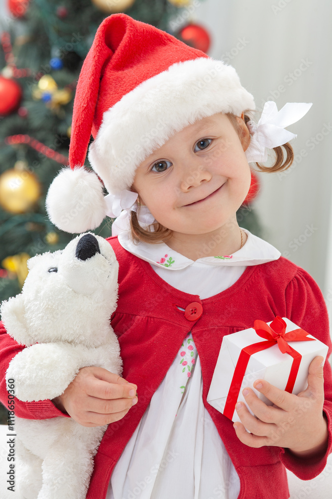 Portrait of little cute girl in Santa Claus costume with Christmas present