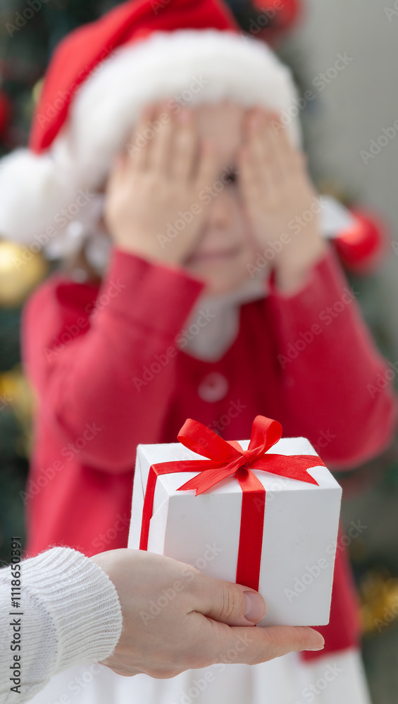 Portrait of little cute girl in Santa Claus costume with Christmas present