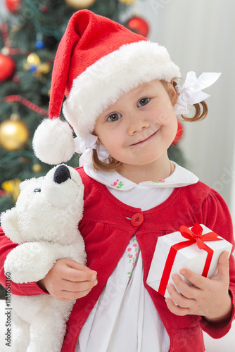 Obraz na płótnie Portrait of little cute girl in Santa Claus costume with Christmas present w salonie