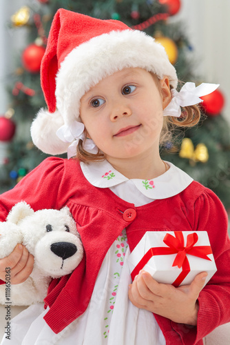 Portrait of little cute girl in  Santa Claus costume  with Christmas present
