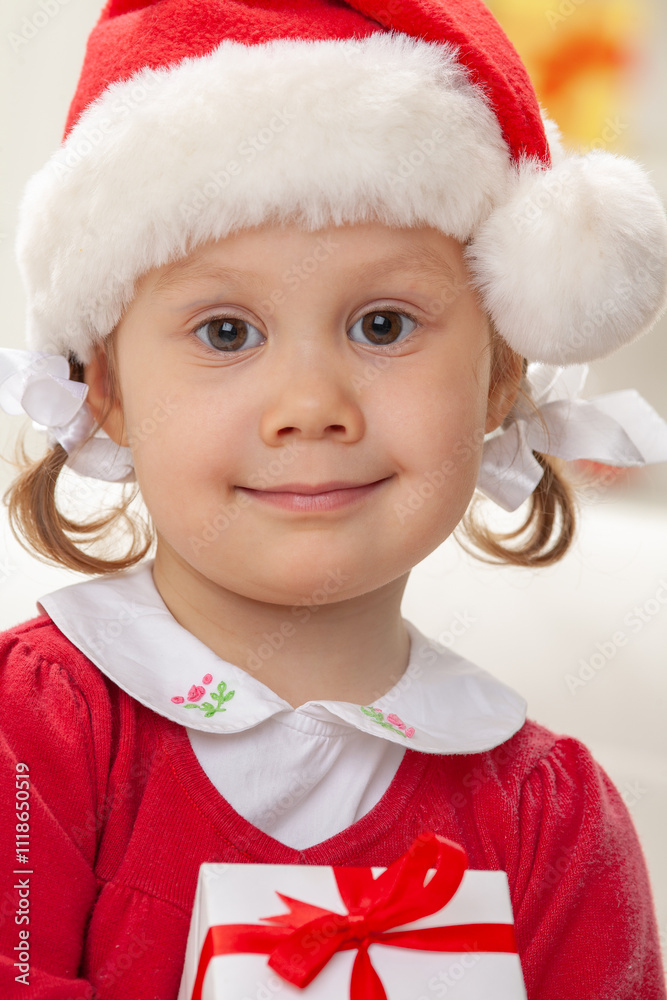 Portrait of little cute girl in Santa Claus costume with Christmas present