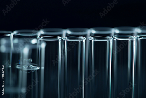 Clear glass test tubes arranged neatly on a dark surface