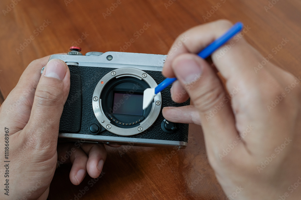 Cleaning the camera sensor with cleaning swab from dust and dirt on wooden table and. Cleaning and care of the camera sensor. The concept of care for professional photographic equipment. Cleaning the camera sensor with cleaning swab from dust and dirt on wooden table and. Cleaning and care of the camera sensor. The concept of care for professional photographic equipment.