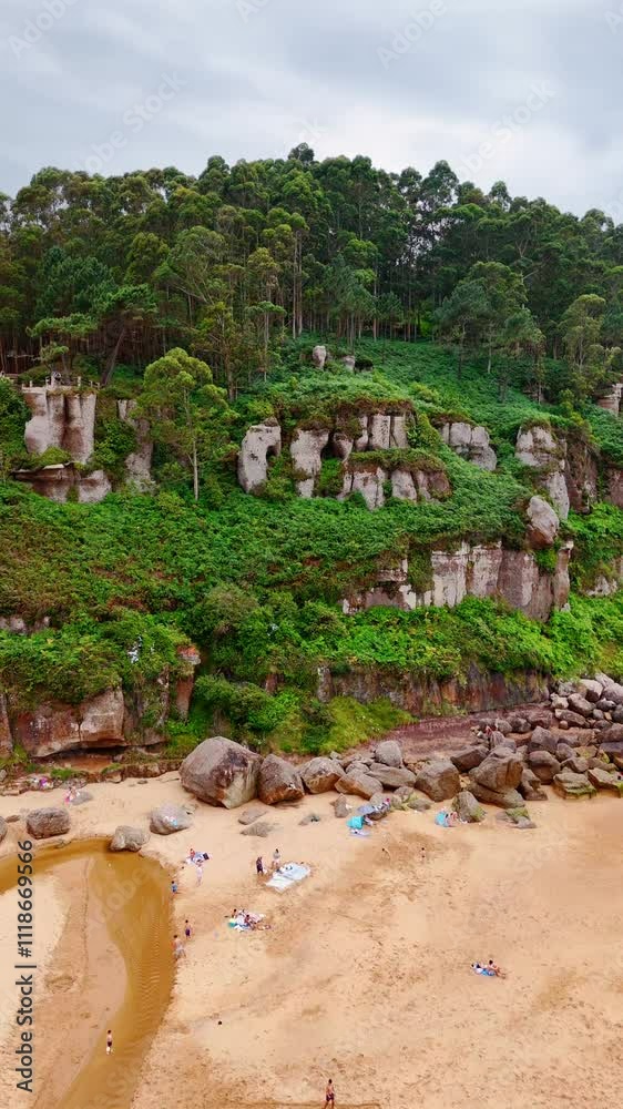 People resting on the sandy beach of the sea. Beautiful rock covered with greenery is at backdrop. Vertical video. People resting on the sandy beach of the sea. Beautiful rock covered with greenery is at backdrop. Vertical video.