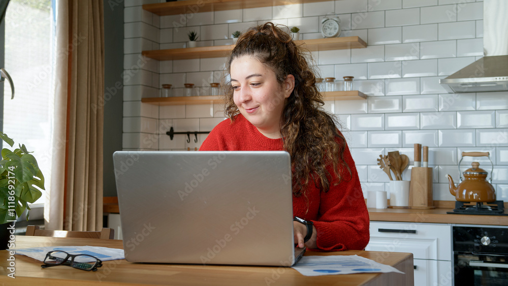 A cheerful woman in a modern kitchen uses her laptop, enjoying a relaxed moment while working or studying from home.
A cheerful woman in a modern kitchen uses her laptop, enjoying a relaxed moment while working or studying from home.