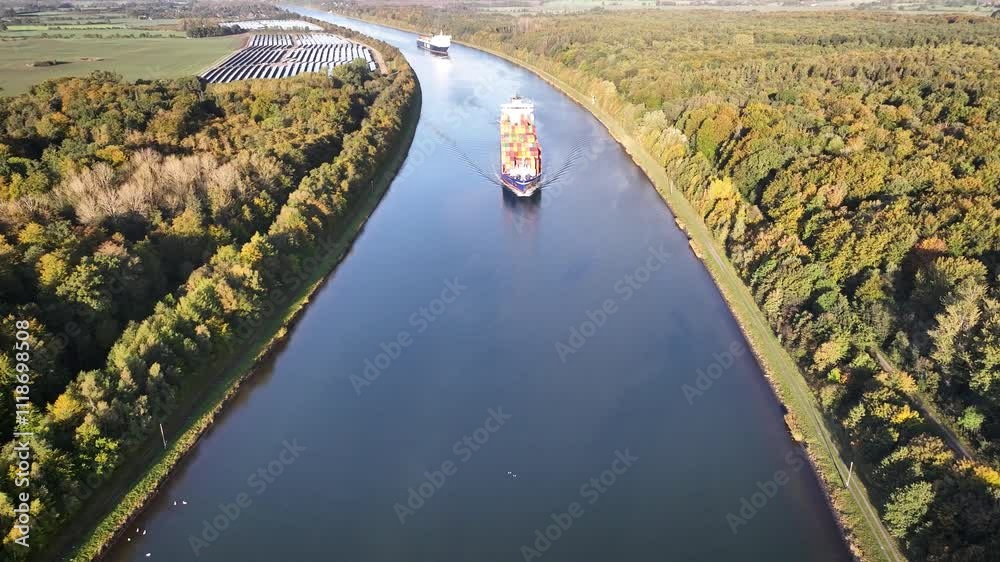 Container ship and car ferry navigate the Kiel Canal alongside vast solar panel fields and wind turbines, set against a backdrop of forest. Container ship and car ferry navigate the Kiel Canal alongside vast solar panel fields and wind turbines, set against a backdrop of forest.