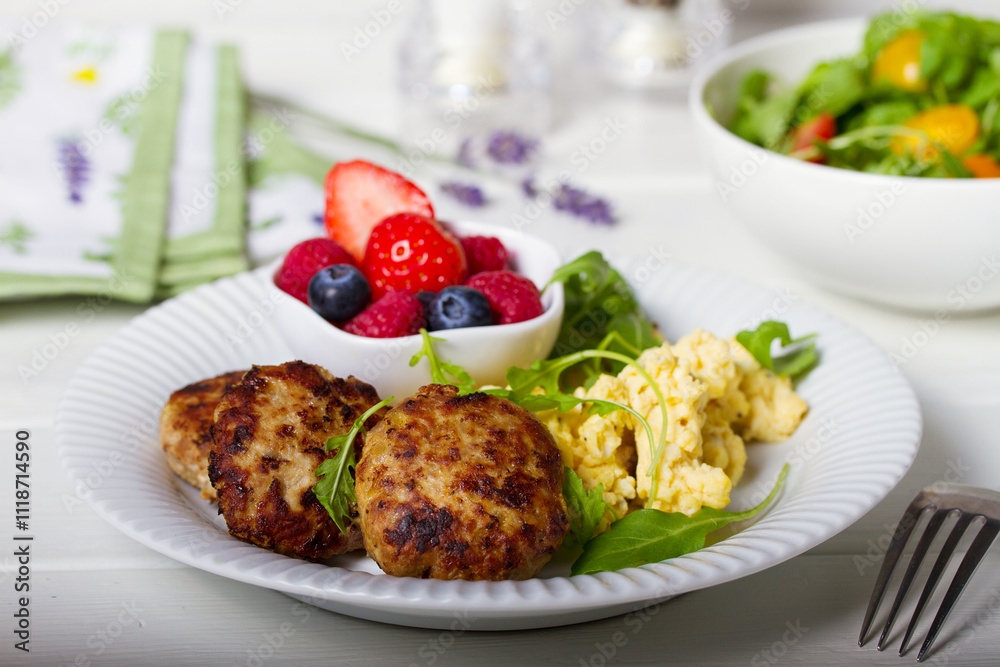 Turkey burgers with scrambled eggs and berries on white wooden background Turkey burgers with scrambled eggs and berries on white wooden background