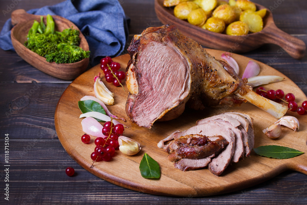 Roasted leg of lamb on serving board with potatoes and broccoli Roasted leg of lamb on serving board with potatoes and broccoli