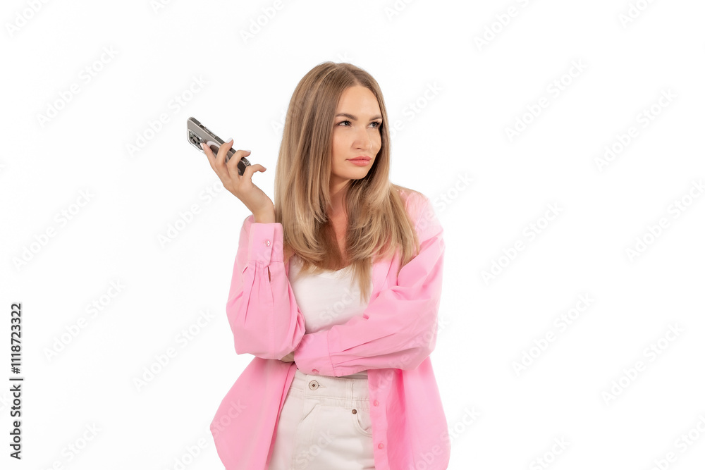 A woman in a pink shirt holds a smartphone, displaying a thoughtful expression while standing against a white background