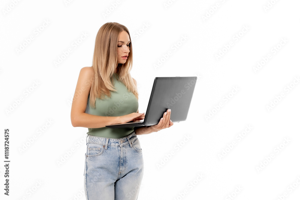 Naklejka premium Young woman in casual attire using a laptop while standing against a white background