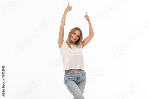 Young woman expressing joy with thumbs up gesture in a bright studio setting during the daytime