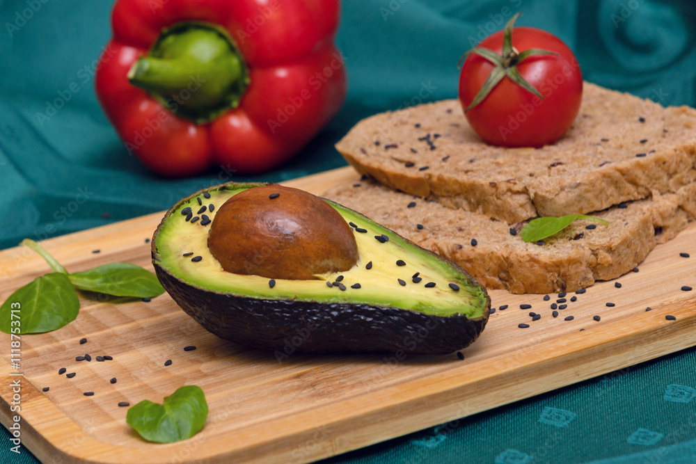 Ripe Avocado with Seed on a Wooden Board with Seeded Bread, Tomato, Spinach Leaves, and Black Sesame Ripe Avocado with Seed on a Wooden Board with Seeded Bread, Tomato, Spinach Leaves, and Black Sesame
