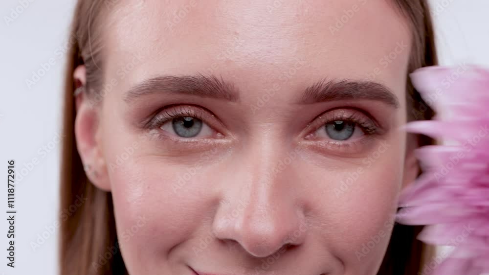 Portrait of attractive girl with healthy clean skin and beautiful make-up. Aesthetic cosmetology and makeup concept.She holds a flower near her face Portrait of attractive girl with healthy clean skin and beautiful make-up. Aesthetic cosmetology and makeup concept.She holds a flower near her face