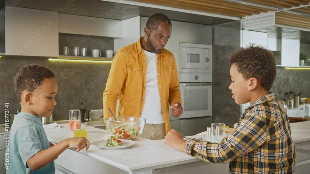 African American man with his small sons sitting at dining table and eating healthy vegetables salad. Hungry people tasting vegetarian food. Useful nutrition. Diet meal. Concept of family. African American man with his small sons sitting at dining table and eating healthy vegetables salad. Hungry people tasting vegetarian food. Useful nutrition. Diet meal. Concept of family.