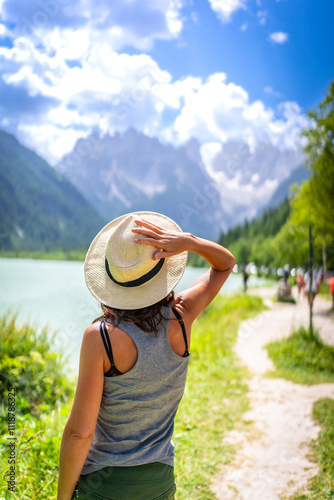 Tourist holding her hat while admiring the dolomites landscape in summer photo