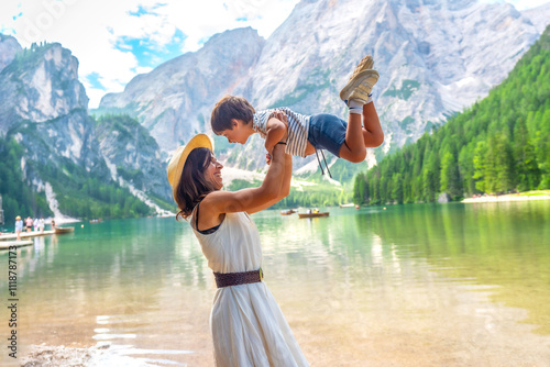 Foto Mother lifting son, enjoying lake braies in dolomites mountains