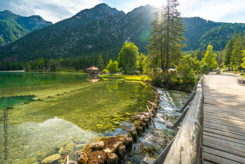 Fototapeta Naklejka Na Ścianę i Meble -  Wooden bridge crossing the clear waters of lake dobbiaco in the dolomites