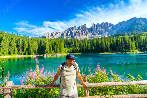 Tourist enjoying breathtaking view of lake carezza and dolomites in summer, italy