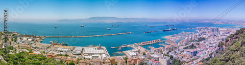 Cable car ascending over Gibraltar city and harbor with cargo ships in the bay