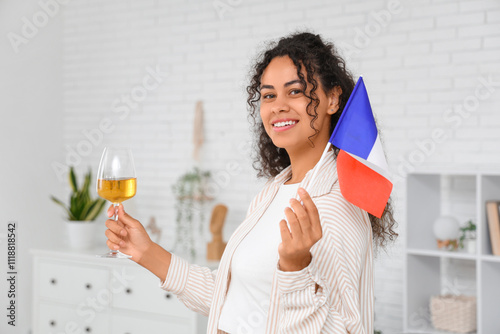 Beautiful young happy African-American woman with flag of France and glass of wine at home photo