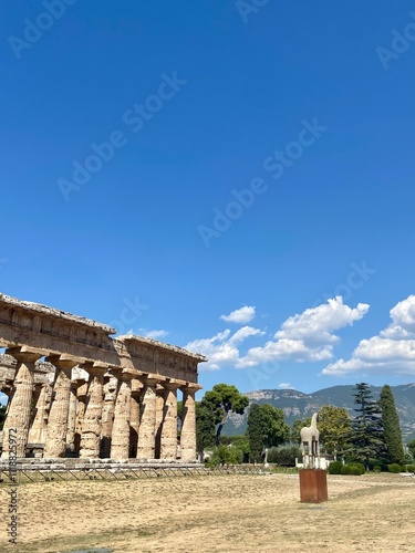 Ancient Greek Temple Ruins of Paestum with Clear Blue Sky, Verdant Landscape, and Historic Architecture in Southern Italy