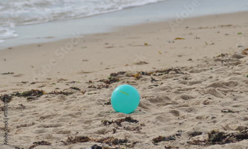 Blue-green balloon, left on the beach sand, with a message of freedom printed on it