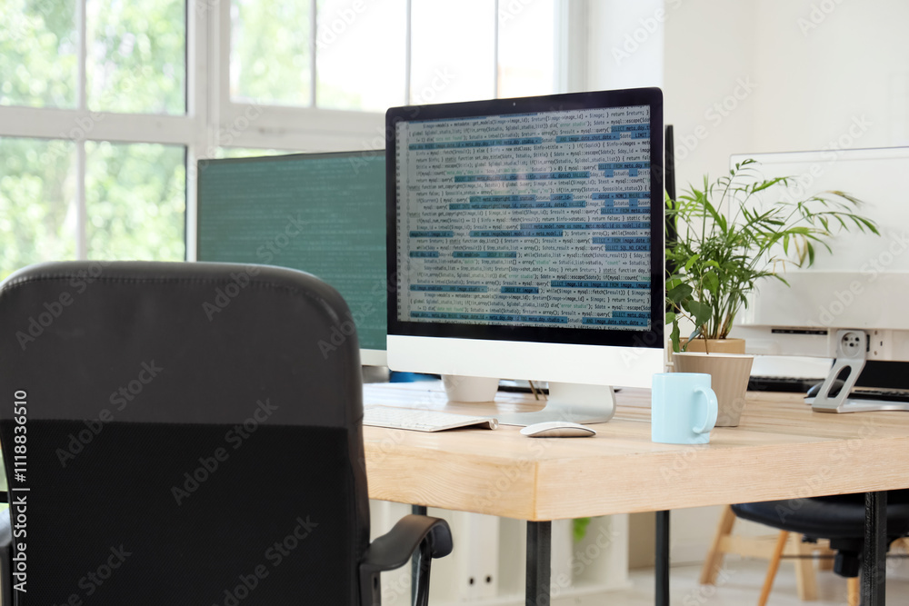 Computer monitors with code on programmer's desk in office Computer monitors with code on programmer's desk in office