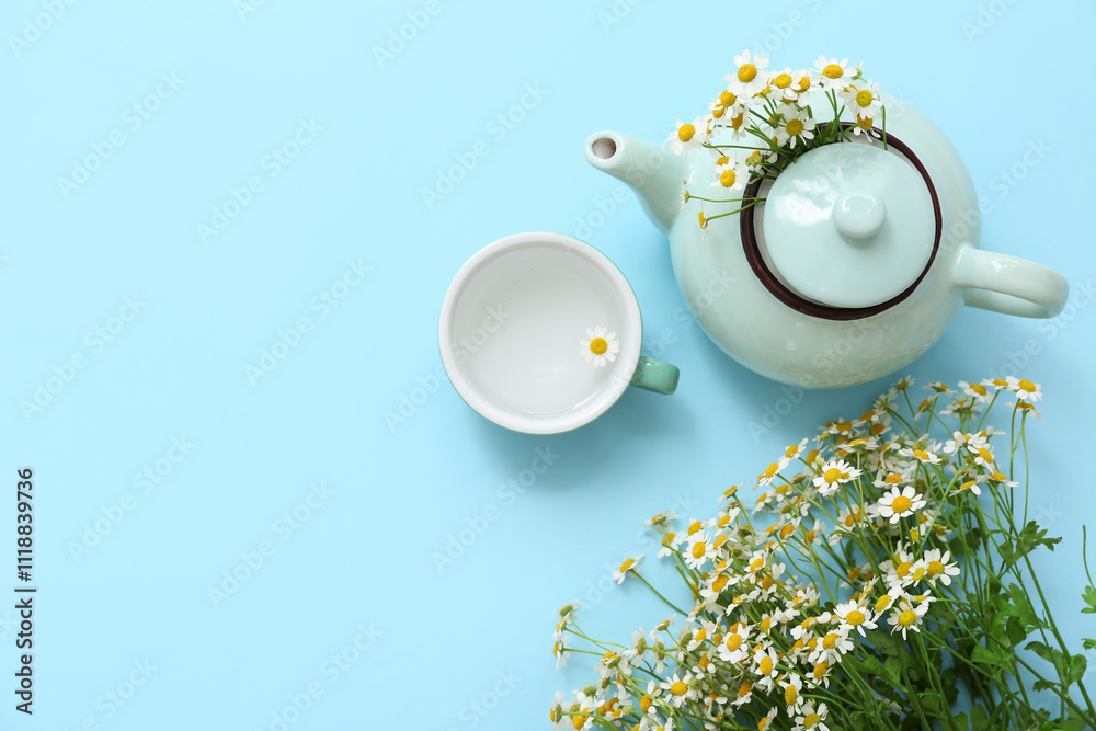 Teapot and cup with chamomile flowers on blue background. Top view Teapot and cup with chamomile flowers on blue background. Top view
