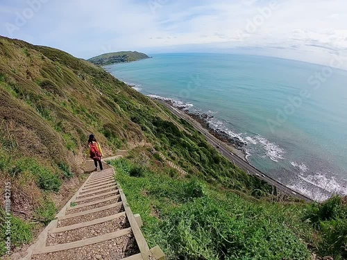 A lady walking down the stairway with panoramic views along the Kapiti Coast from the Escarpment walking track on the sunny day 