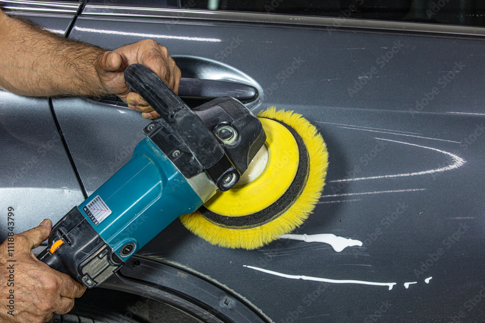 Professional car detailer holds air random orbital sander or dual action polisher in hand while polishing the paint surface of gloss gray paint. Car detail, car wash and paint sealant concept. Professional car detailer holds air random orbital sander or dual action polisher in hand while polishing the paint surface of gloss gray paint. Car detail, car wash and paint sealant concept.