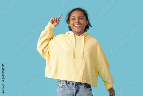 Emotional African-American girl with raised index finger on blue background photo