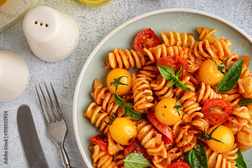 Plate of delicious fusilli pasta with tomatoes and basil on grunge background, closeup