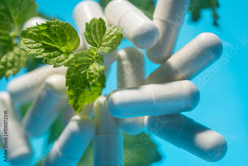 Herbal medicine capsules and fresh mint leaves close-up