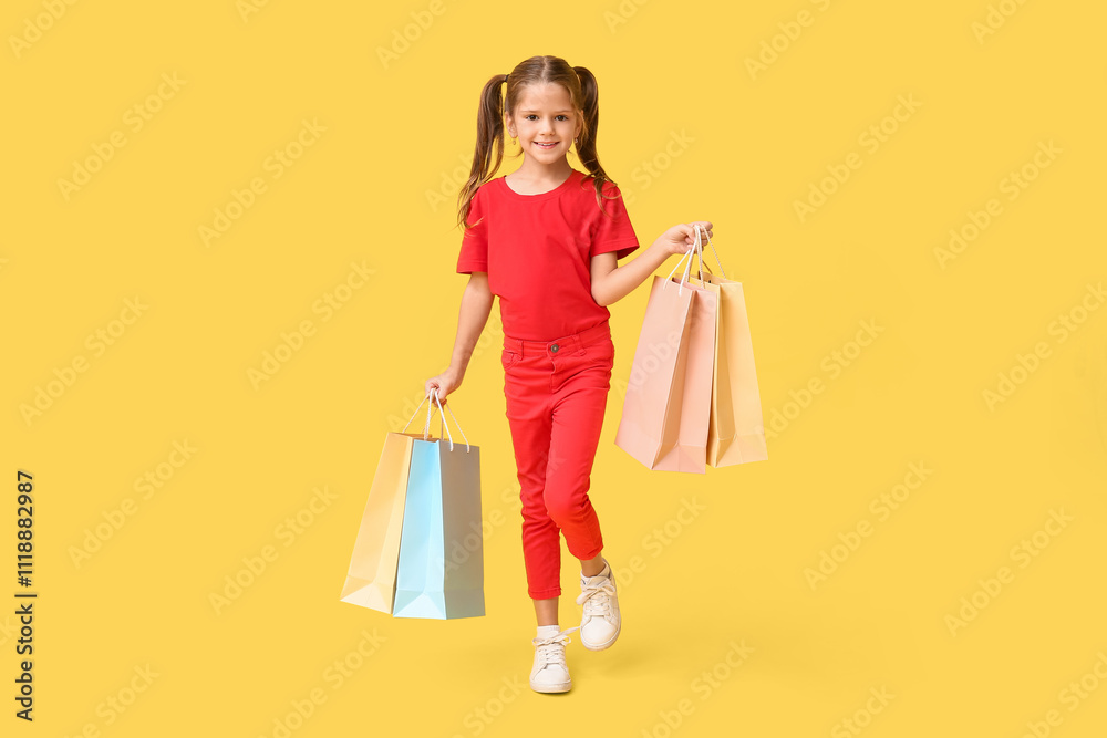 Portrait of happy little girl with shopping bags on yellow background Portrait of happy little girl with shopping bags on yellow background