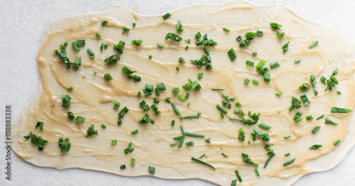 overhead view of sliced scallions on thinly rolled dough, process of making scallion pancakes or cong you bing photo