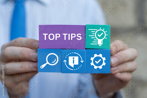 Business man holding colorful blocks sees inscription: TOP TIPS. Top tips business education concept. photo