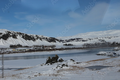 A snow-covered field in Iceland with reflective water pools under the sky.