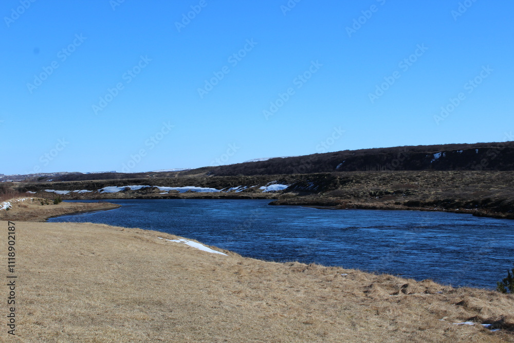 A winding river in Iceland surrounded by grassy plains. A winding river in Iceland surrounded by grassy plains.
