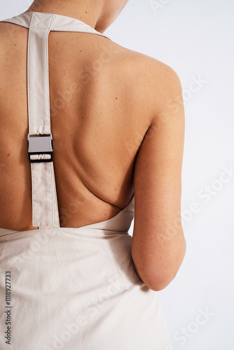 Back view of woman wearing beige outfit with strap detail.