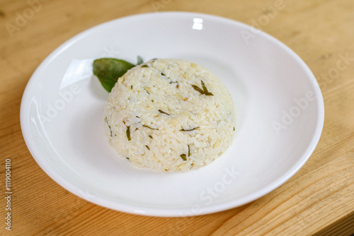 Lime leaf rice on wooden table. Fried onion on top. thisi is Indonesian cuisine on rattan plate. Nasi daun jeruk