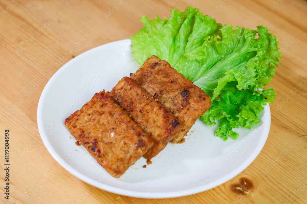 Tempe Bacem is a traditional food of Central Java, the tempeh is flavored with brown sugar and then fried, served on wicker bamboo plate Tempe Bacem is a traditional food of Central Java, the tempeh is flavored with brown sugar and then fried, served on wicker bamboo plate
