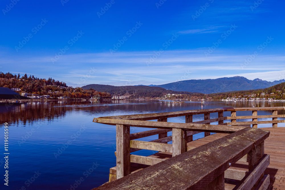 Wooden pier overlooking placid ocean inlet with forested mountains on horizon. Wooden pier overlooking placid ocean inlet with forested mountains on horizon.