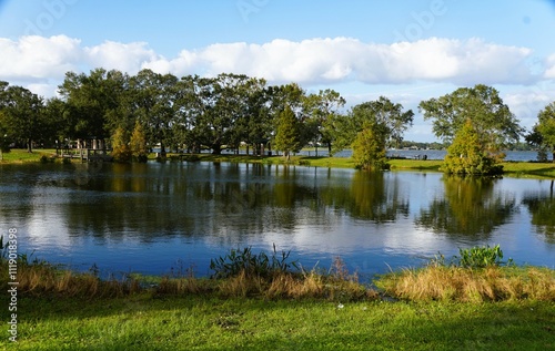 Fototapeta Naklejka Na Ścianę i Meble -  A peaceful park setting with a calm pond reflecting the surrounding trees and sky near Lake Hartridge Nature Park, Winter Haven, Florida, U.S